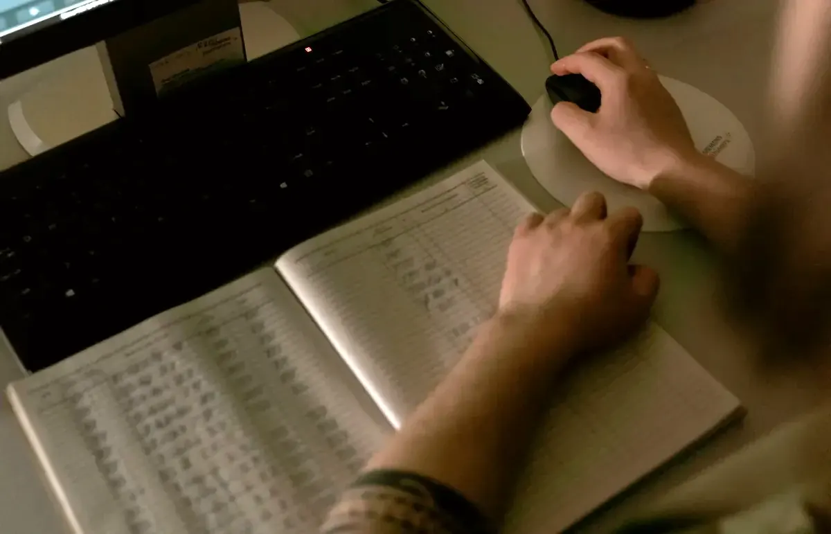 Healthcare worker reviewing medical records on a computer and written register